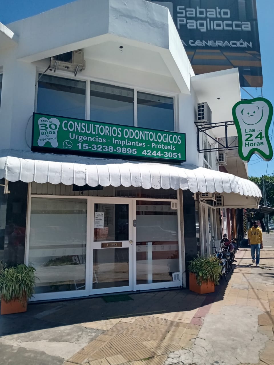 Fachada del consultorio dental en Temperley con ventanales vidriados y recepción visible desde la vereda